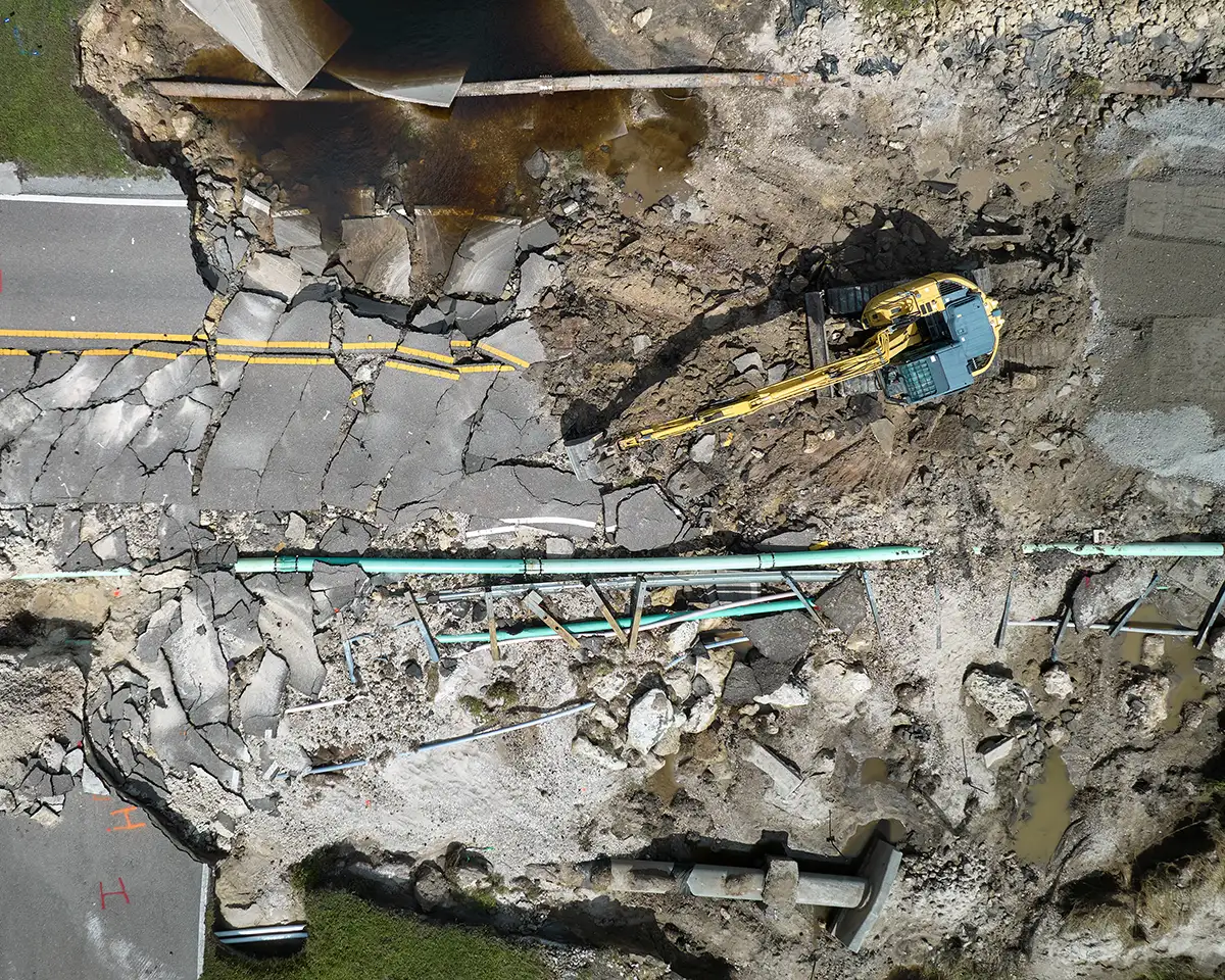 Aerial view of reconstruction of damaged road bridge destroyed by river after flood water washed away asphalt.